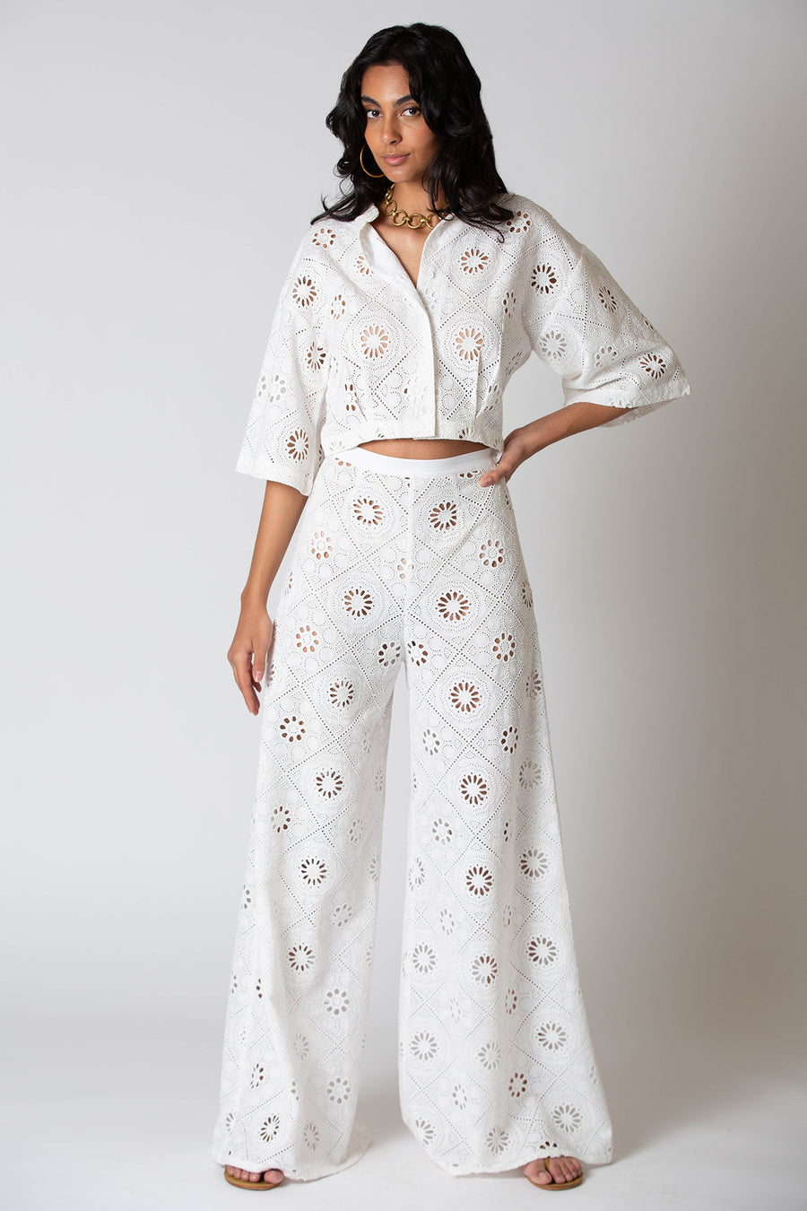 This is a photo of a woman posing in matching, white embroidered top and pants.