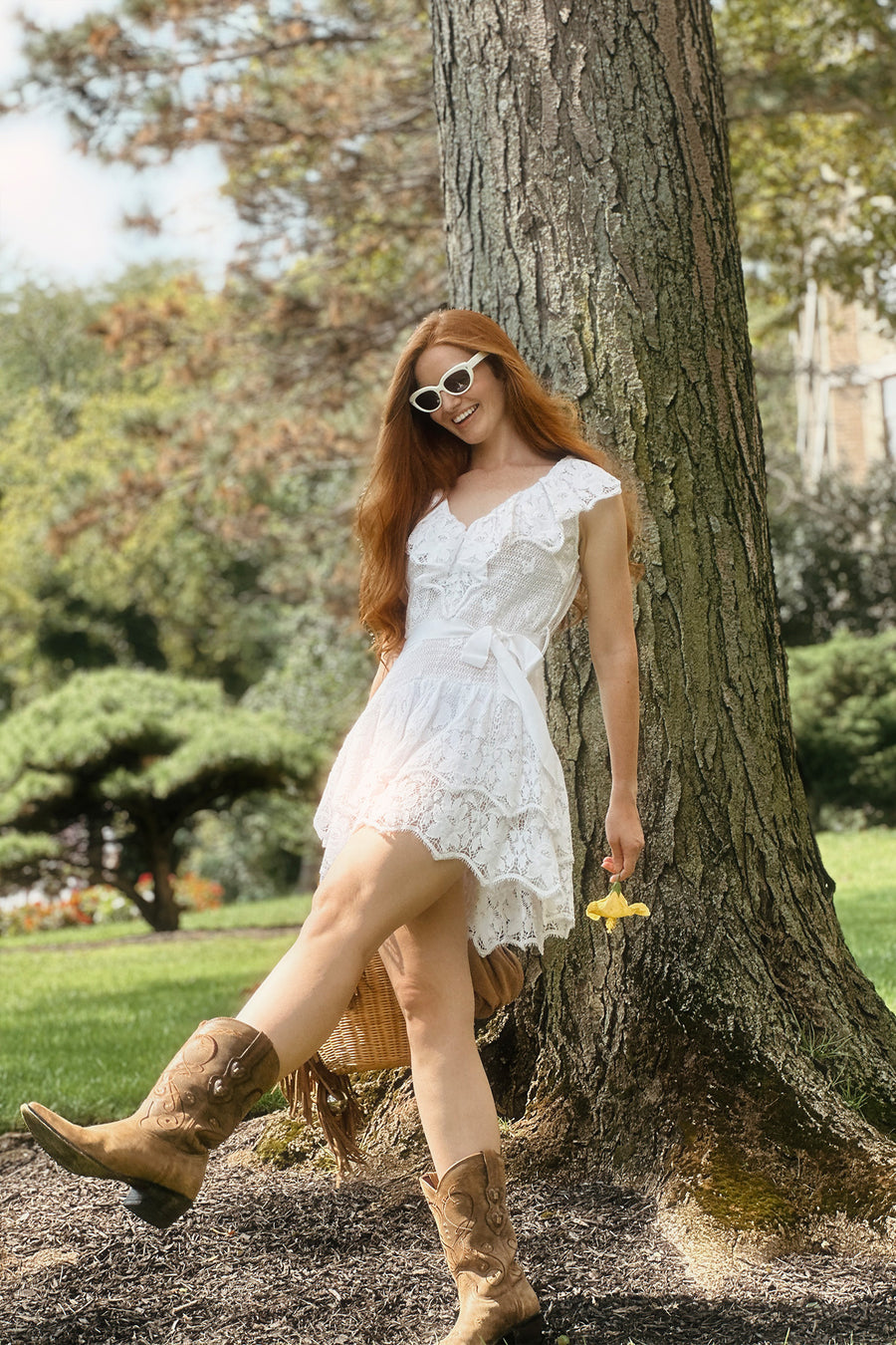 This is a photo of a woman wearing a white, lace dress with layered ruffles that end above the knee.