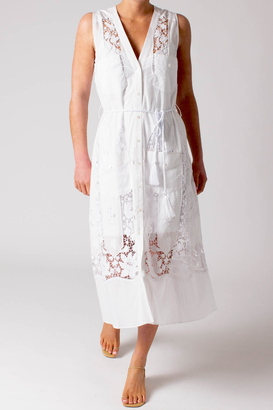 This photo shows a woman wearing a long white dress with lace detailing and a rope tie waist. 