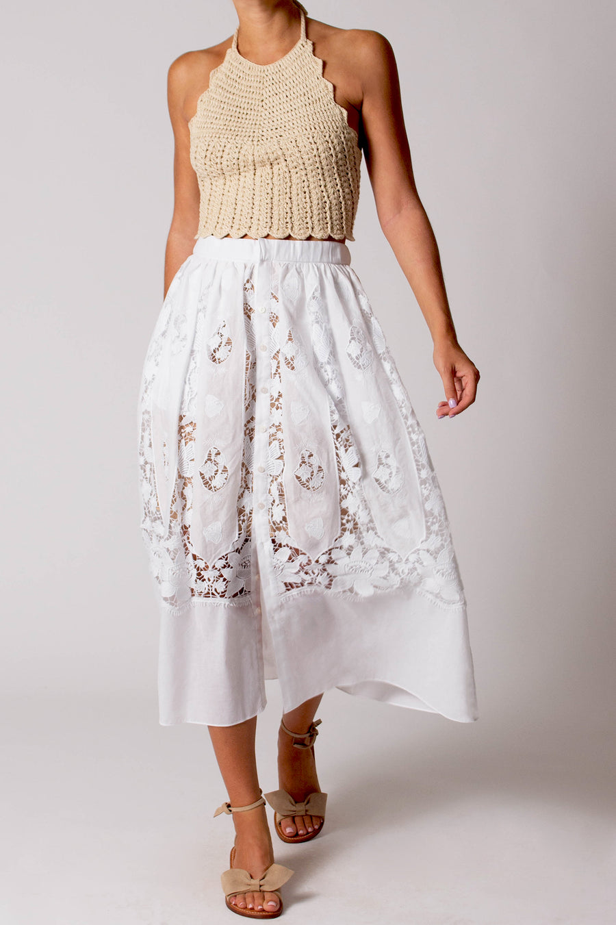 This photo shows a woman wearing a long white skirt with buttons and lace detailing.