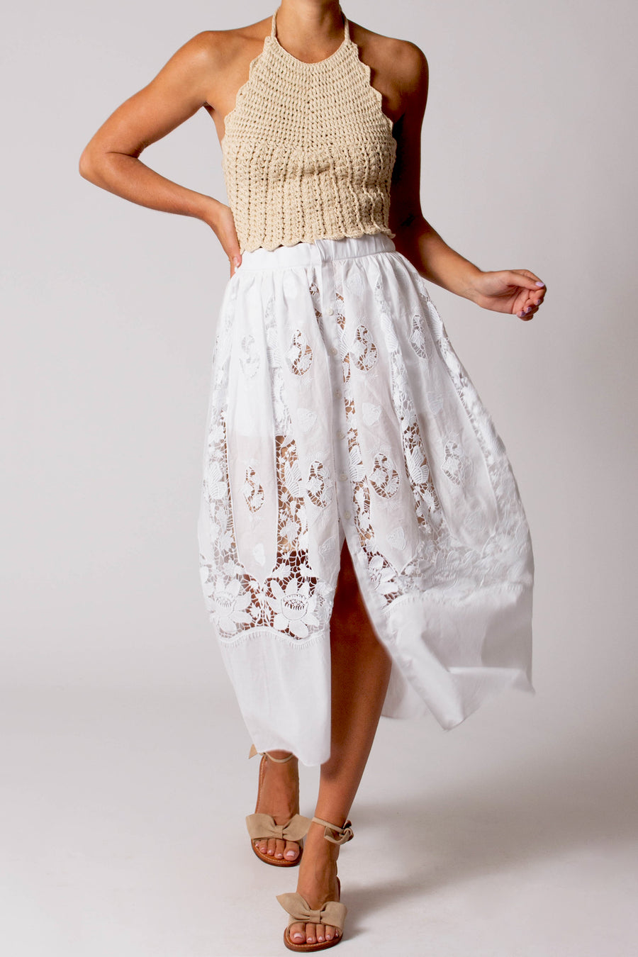 This photo is of a woman wearing a long, white, button down skirt. The skirt has lace detailing and flows as she walks.
