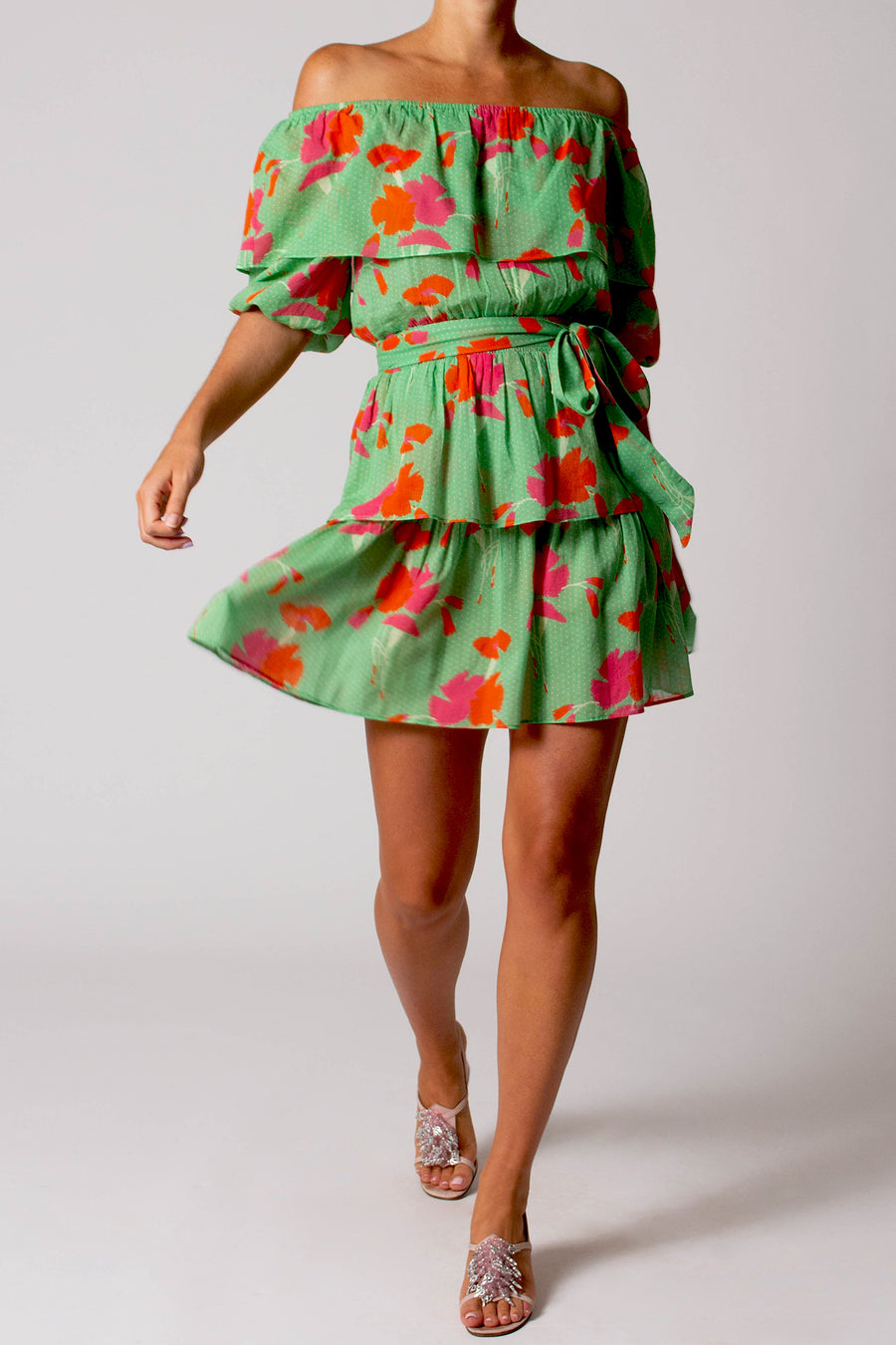 This is the photo of a woman wearing a short green dress with pink and orange flowers on it.