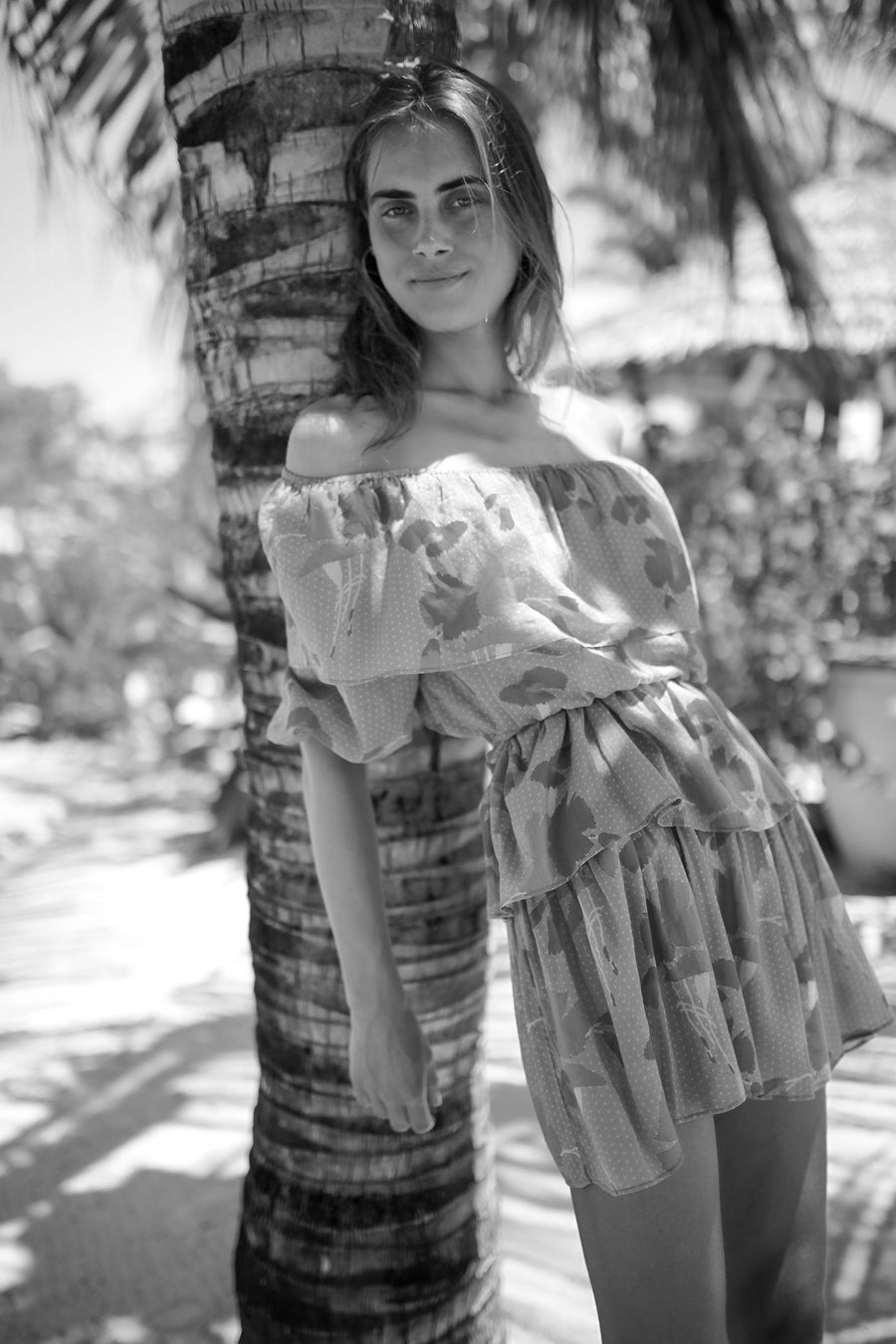 This is a black and white photo of a woman standing outside wearing a short dress.