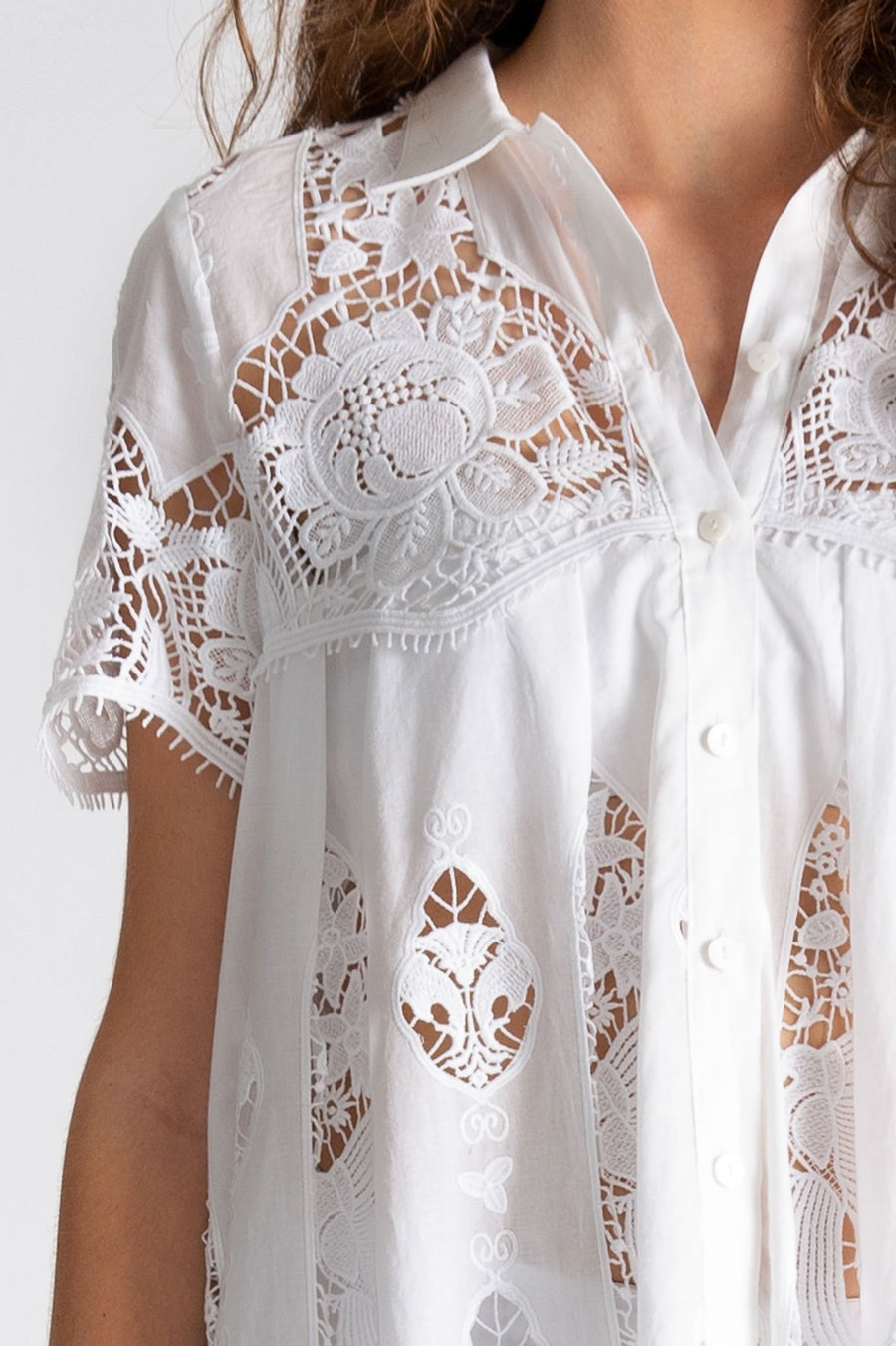 This is a detail photo of the white lace embroidery inspired by hibiscus flowers. The linen collar and button down front are visible here on the babydoll coverup dress.