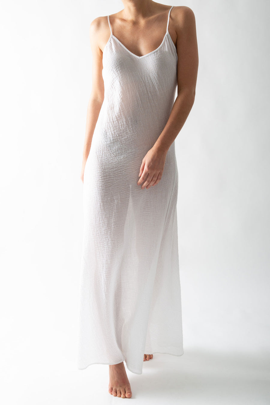 This is a photo of a woman wearing a sheer white slip dress in a cotton gauze material. 