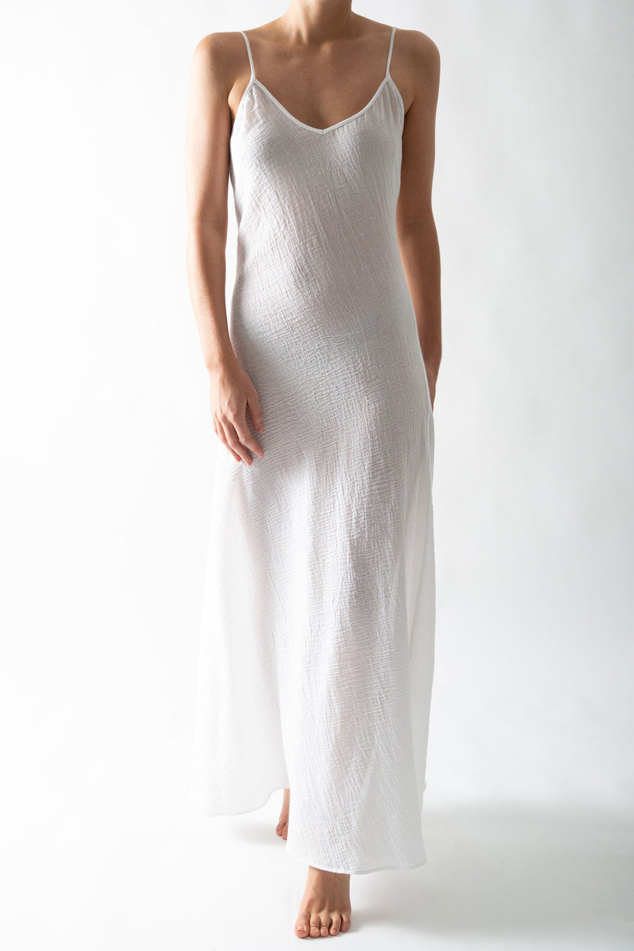 This is a photo of a woman wearing a sheer white slip dress in a cotton gauze material. 