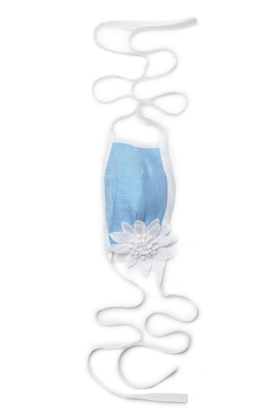 This is a photo of a solid blue linen mask with white ties for around the head and neck and solid white trim around face. There is a removable large white flower on one side, secured with snap button.