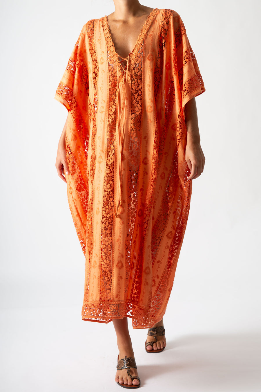 This is a photo of a woman wearing an orange embroidered cover up. She wears this with snakeskin sandals.