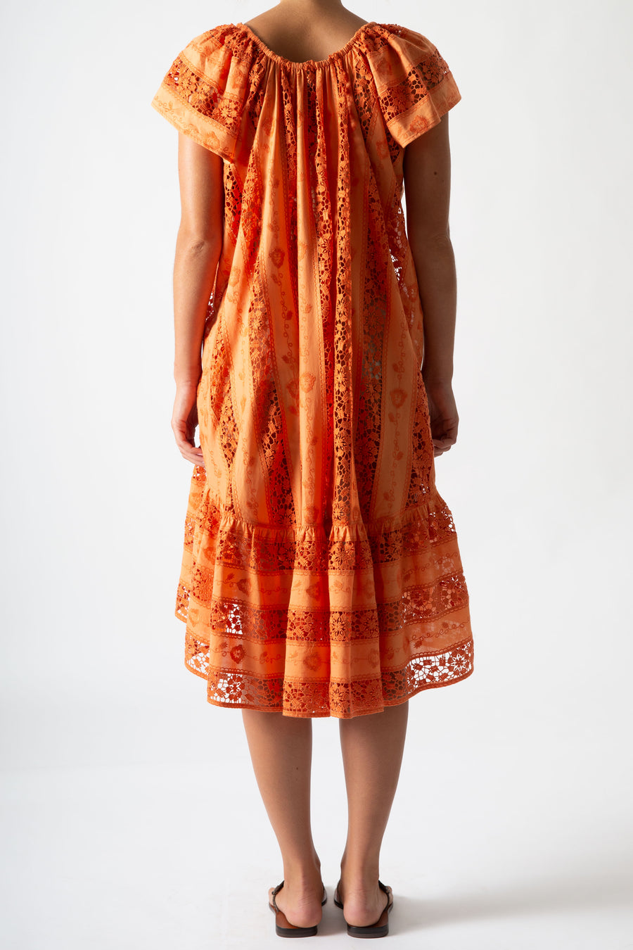 This is a back side photo of a woman wearing an orange embroidered cover up.