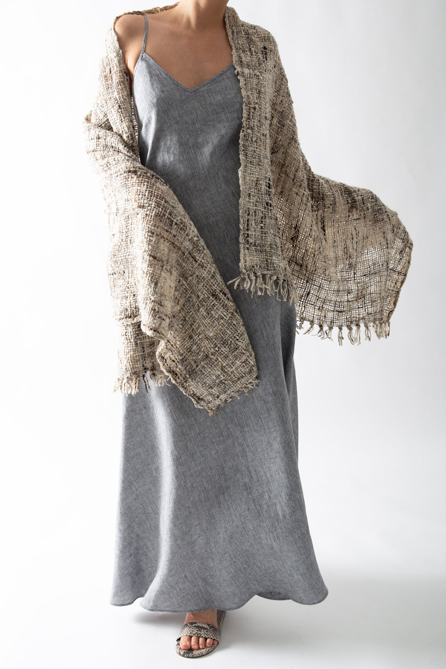 This is another photo of the woman wearing the shawl and slip dress, posing with her arm extended to show the fringe along the edge of the shawl.