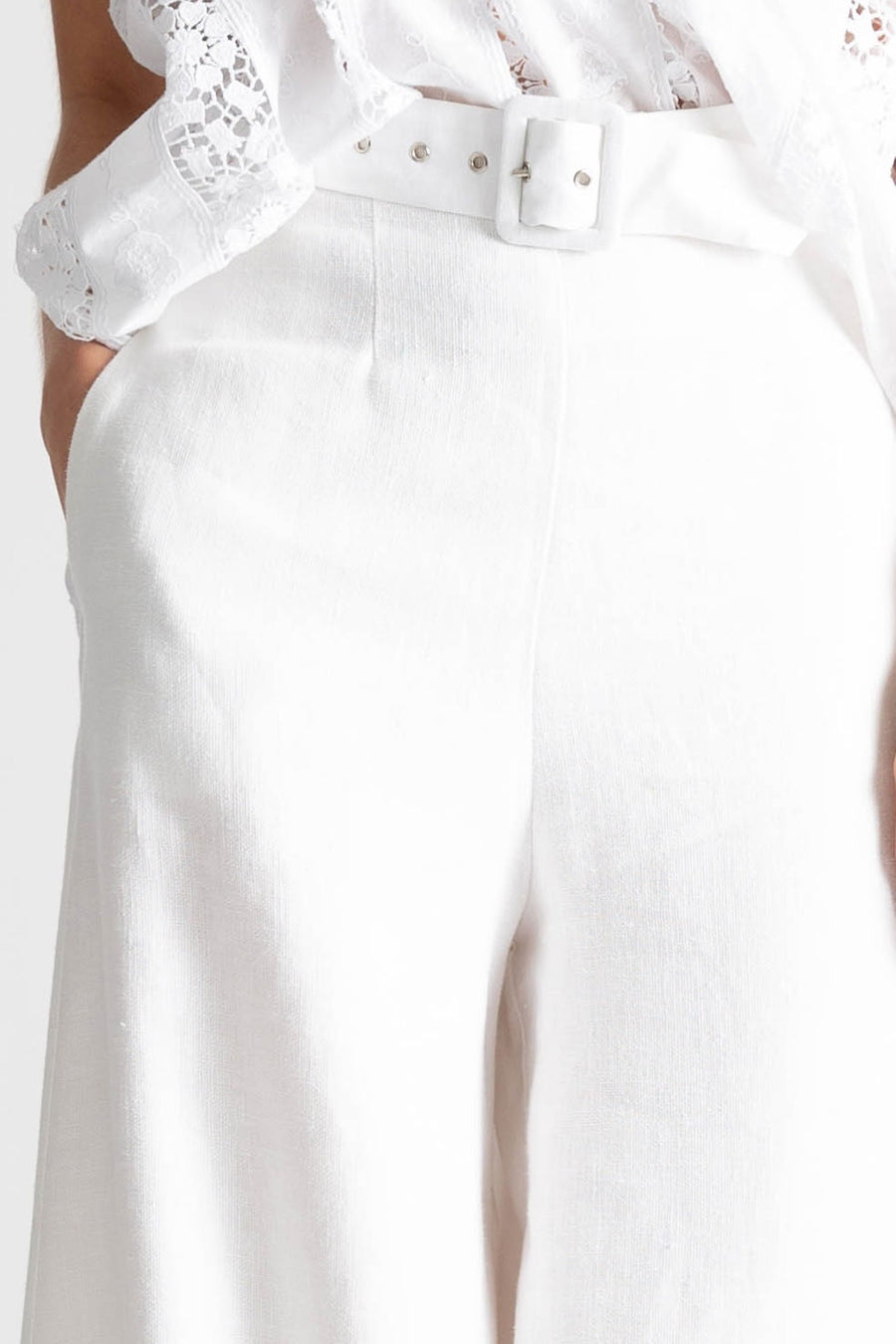 This is a detail photo of high waisted white linen pants with an attached belt and side seam pockets. 
