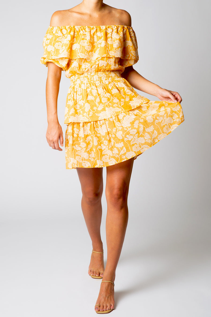 This is a photo of a woman wearing a short and flowy yellow dress with a pattern.